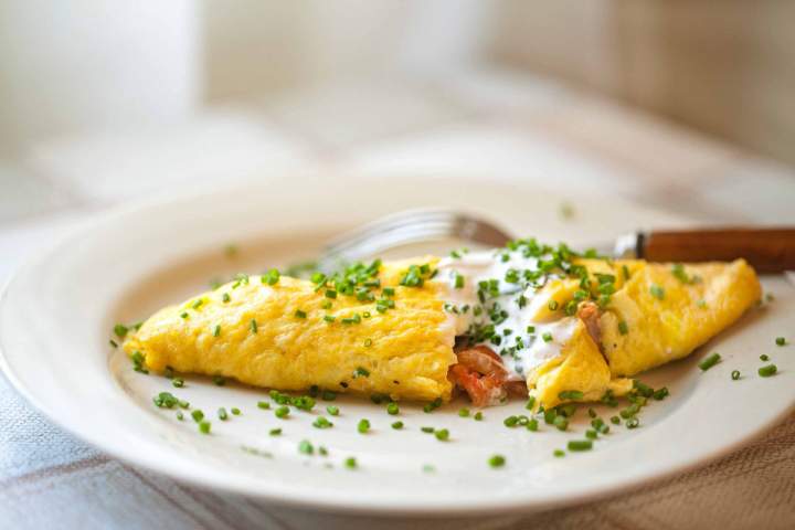 Jajčna omleta s češnjevimi paradižniki, postrežena s kislo smetano in drobnjakom