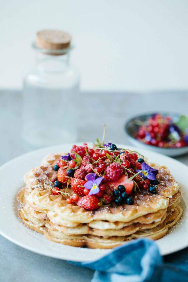 Crisp waffles served with berries and icing sugar