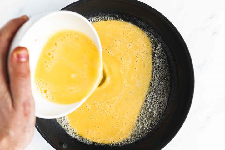 Pouring eggs into a hot pan for Cheesy Scrambled Eggs