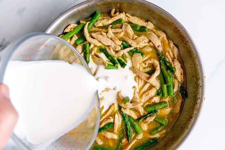 Adding whipping cream to chicken for Creamy Chicken with Asparagus