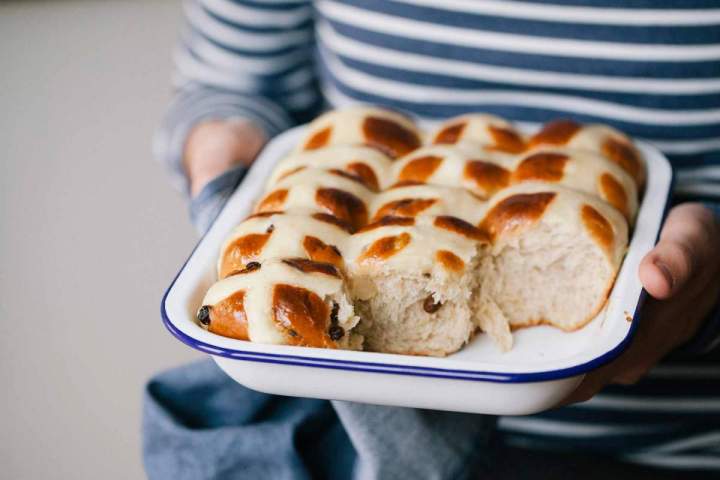 Baked hot cross buns in a baking dish held by Jernej