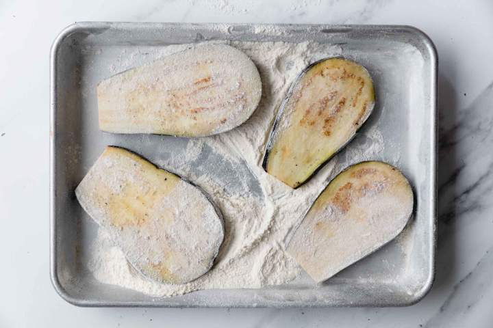 rolling eggplants in flour for Eggplant Parmesan (Melanzane alla Parmigiana)