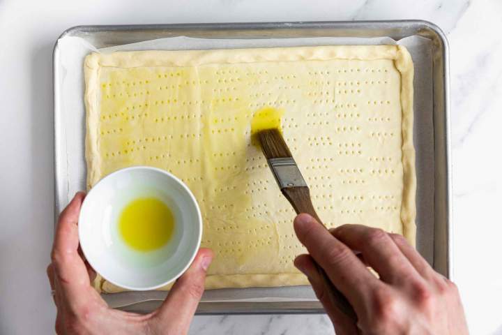 Brushing the puff pastry with olive oil for Puff Pastry Tomato Tart with Mozzarella