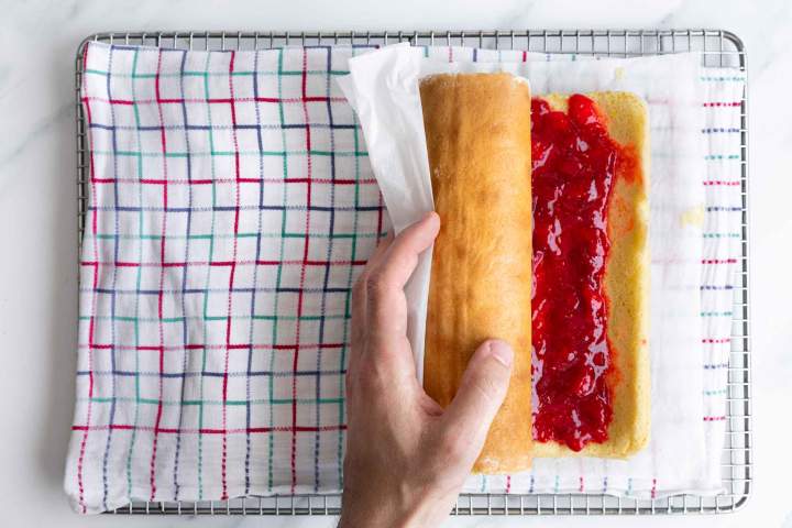 rolling strawberry jam spread on sponge cake