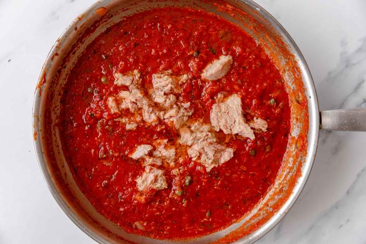 Adding tuna to the tomato sauce for the pasta sauce