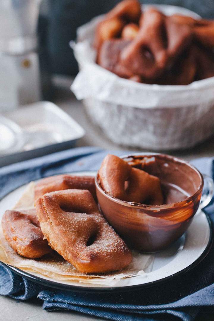 Beignets with cinnamon sugar on a plate with chocolate and coffee