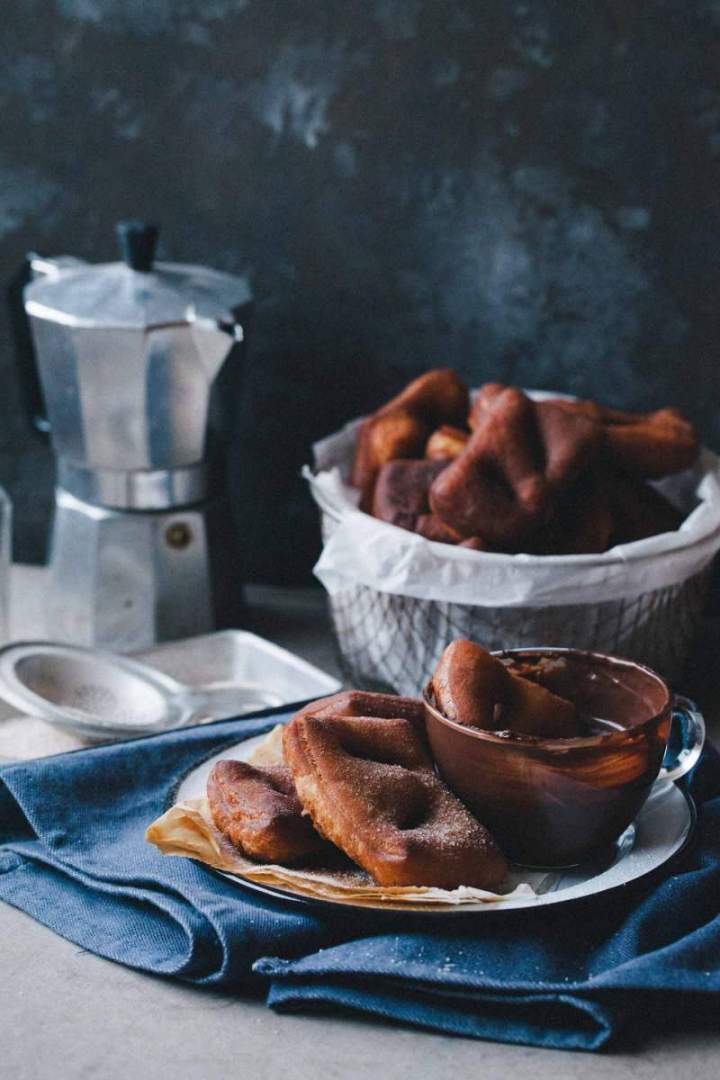 Beignets with cinnamon sugar on a plate with chocolate and coffee