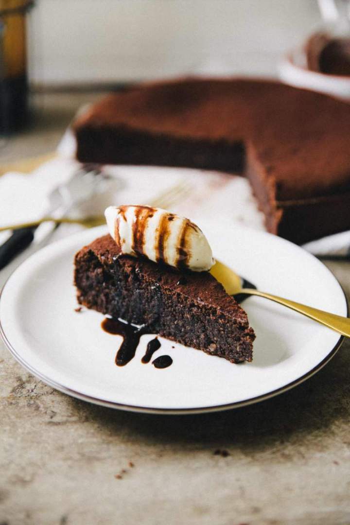 Slice of Flourless espresso chocolate cake served with ice cream and chocolate sauce