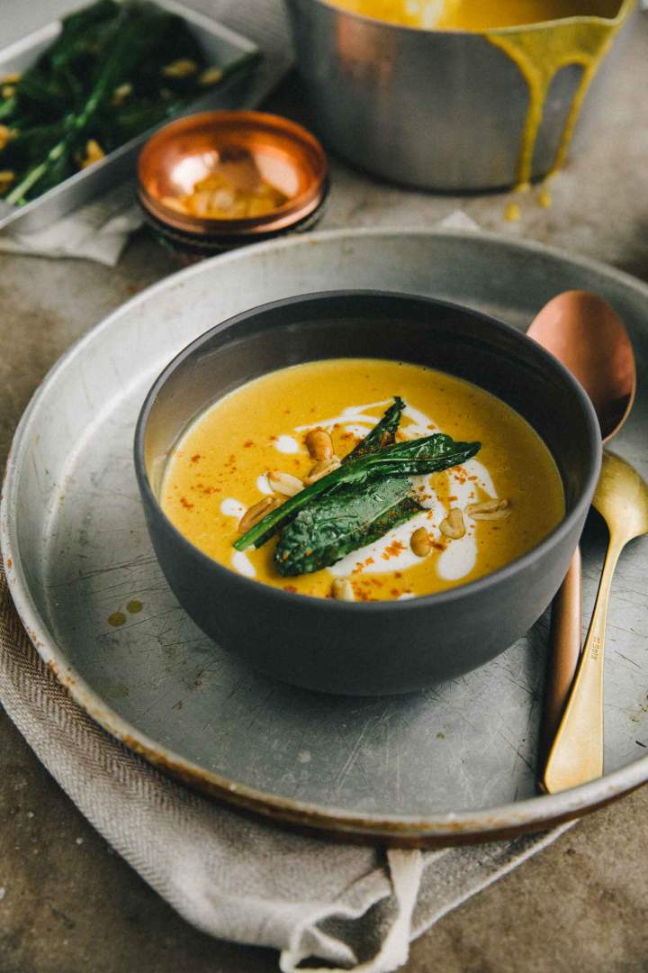 Pumpkin soup with roasted peanuts and kale served in a bowl