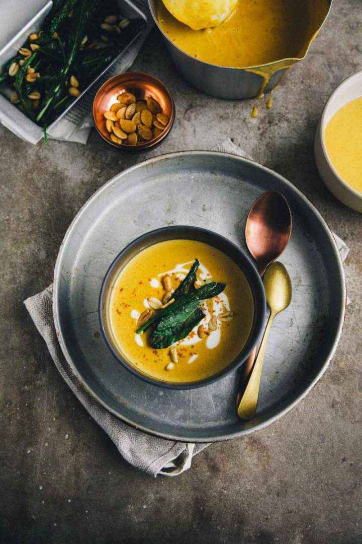 Pumpkin soup with roasted peanuts and kale served in a bowl