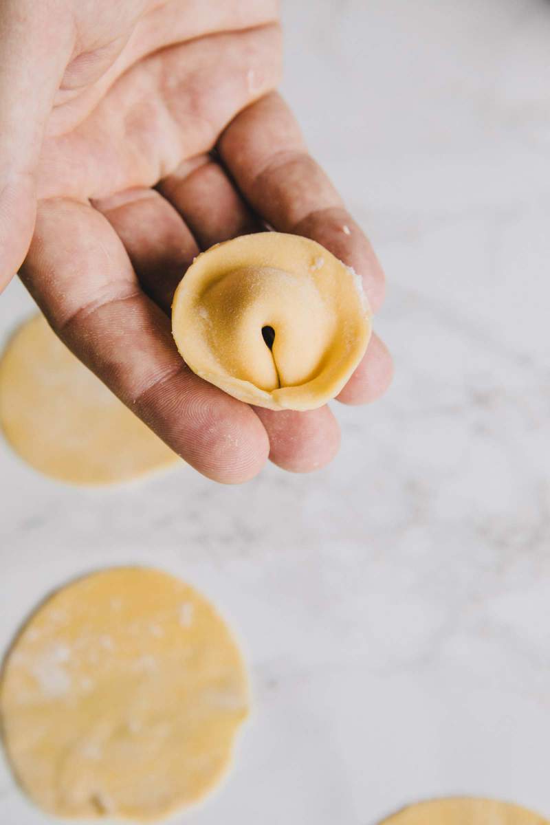 Shaping pasta for Tortellini stuffed with mortadella and lovage sauce