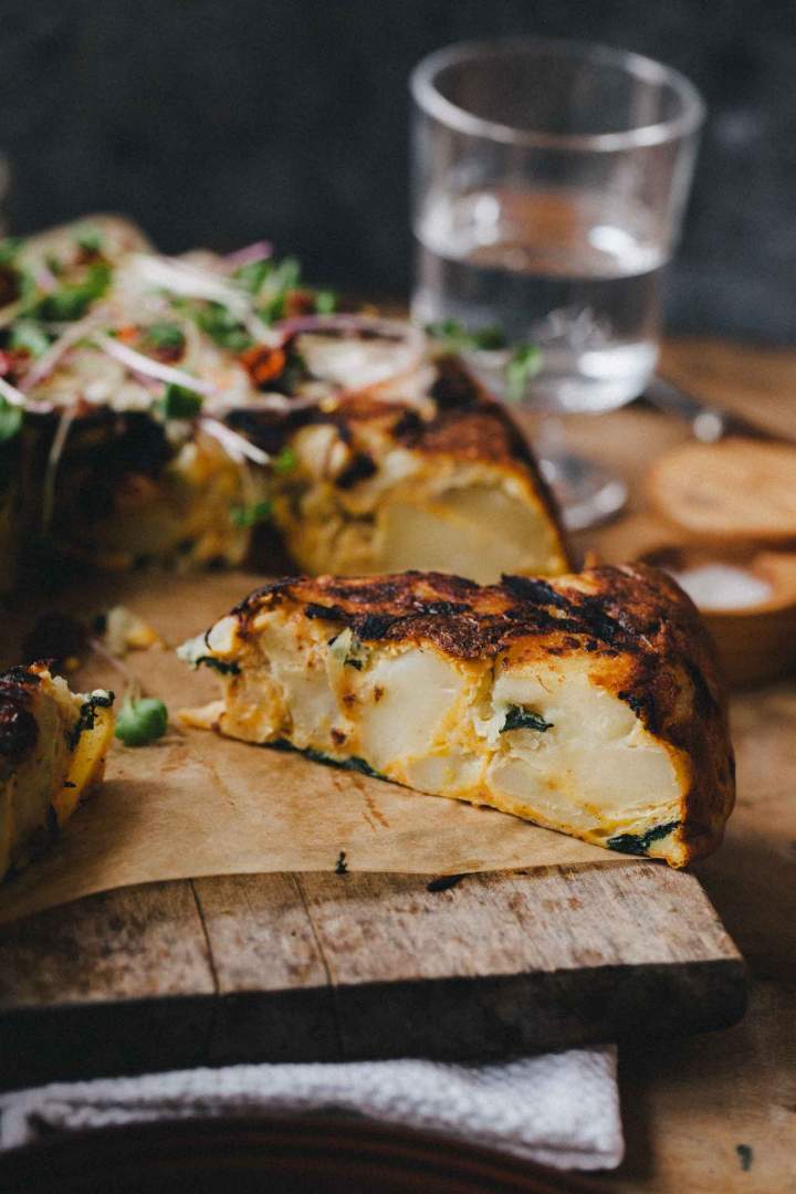 Tortilla de patatas cut on slices and served with herbs